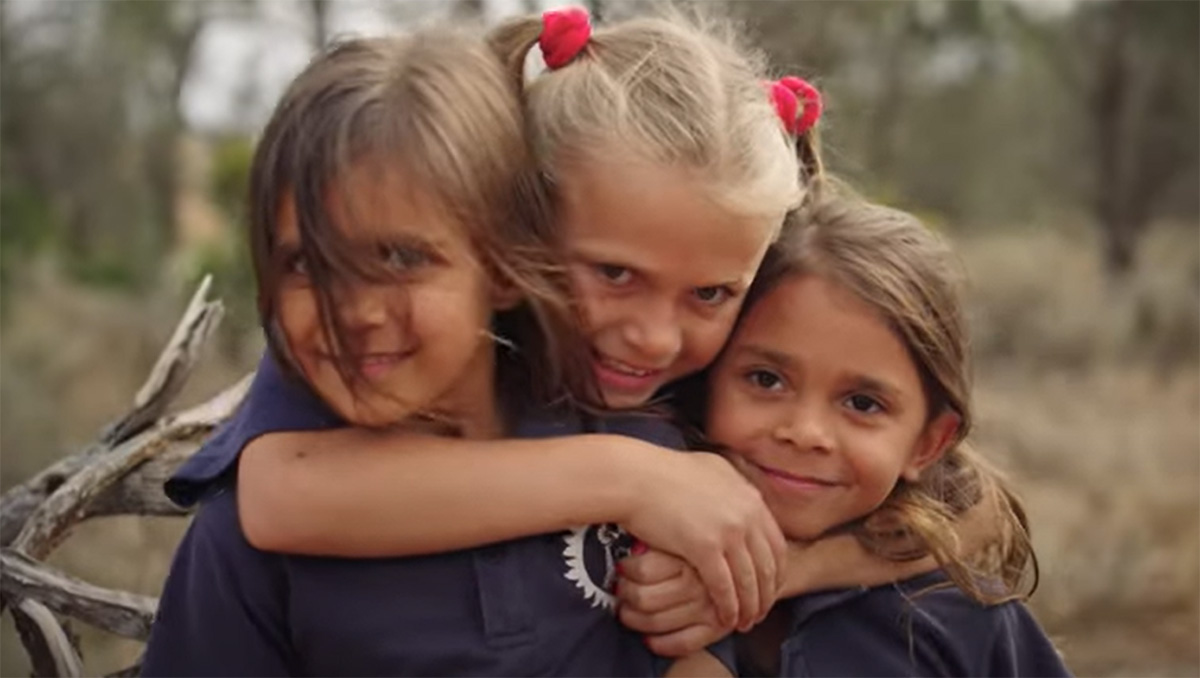 Three Aboriginal children hugging.